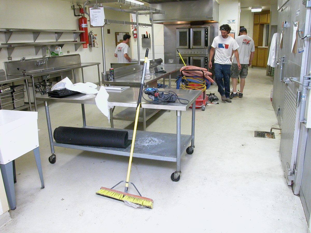 Worn and cracked commercial kitchen floor before coating