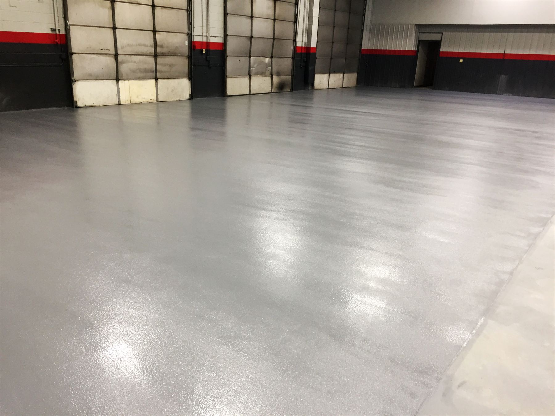 Gray epoxy floor with speckled flake texture and glossy finish in warehouse loading bay