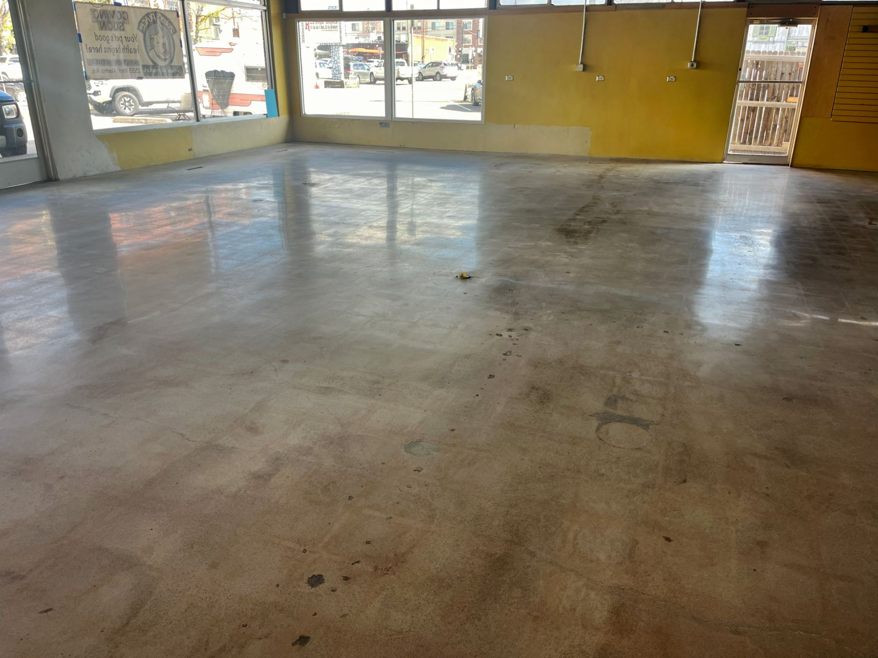 Stained polished concrete floor in an empty storefront with yellow walls and large windows