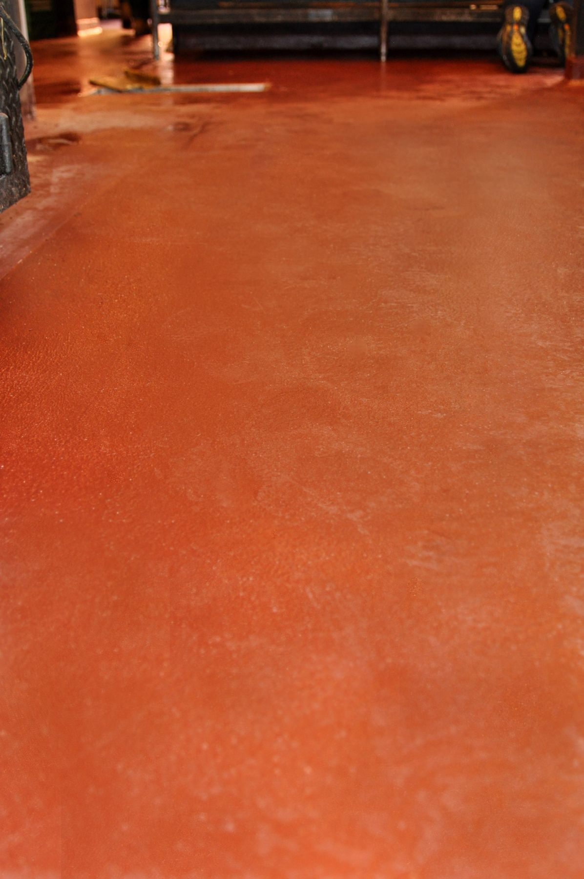 Close view of glossy terracotta red seamless urethane cement floor in a commercial kitchen